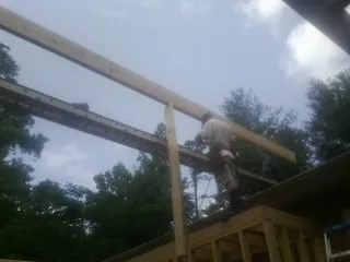 Carpenter setting a ridge beam over a new addition frame — Ice Dam Removal by Roofing Brothers in Oakdale