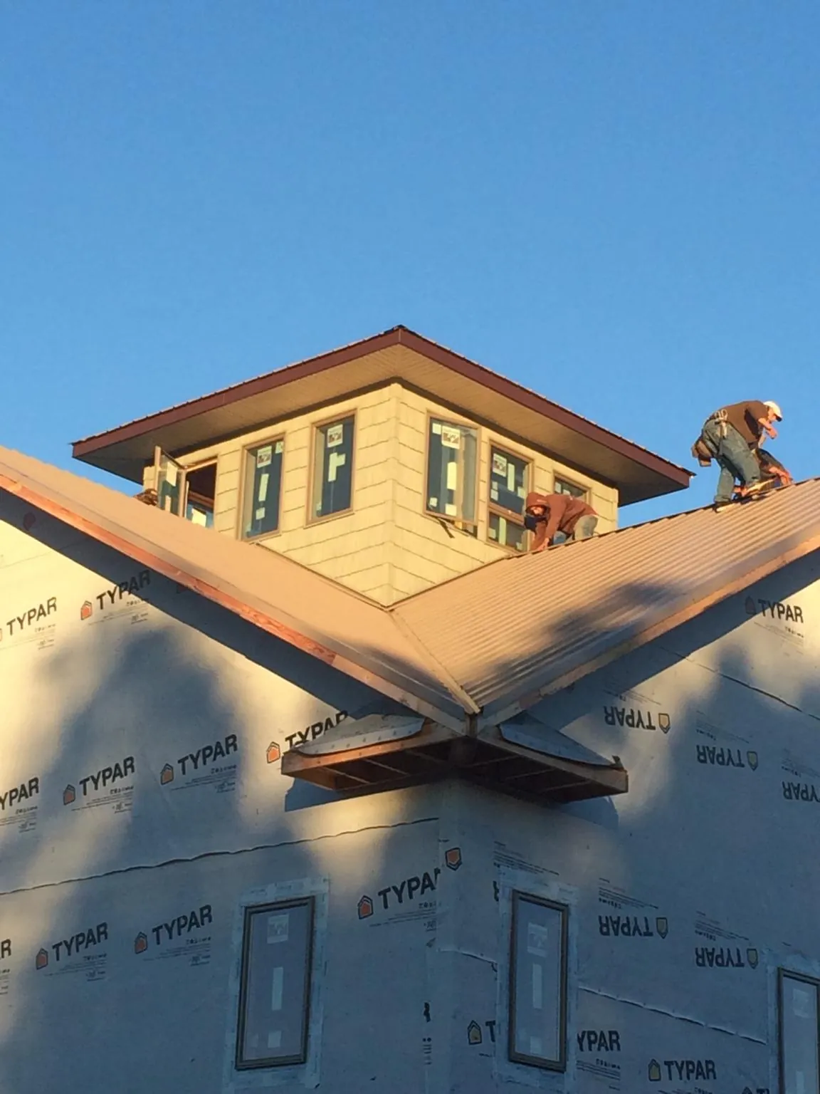 Roofers working around a rooftop cupola on a new metal roof at sunset — Roof Waterproofing in Oakdale by Roofing Brothers
